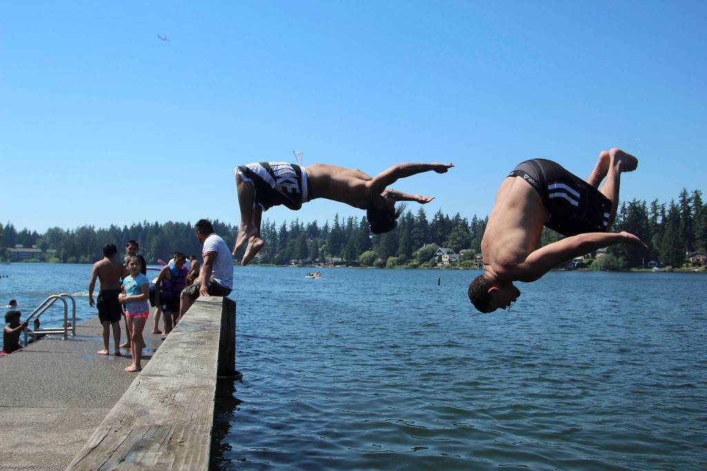 Brothers 29-year-old Marques Swansey, left, and Quincy Swansey, 27, backflip off of the dock at Steel Lake on June 28. Olivia Sullivan/the Mirror