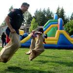 Capt. Brad Chaney of South King Fire competes in a potato sack race with kids at the Kitts Corner Apartments on Aug. 3. Olivia Sullivan/the Mirror