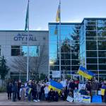 Dozens of people pose for a photo in front of Federal Way City Hall as the Ukrainian flag flies on Feb. 25. Olivia Sullivan/the Mirror