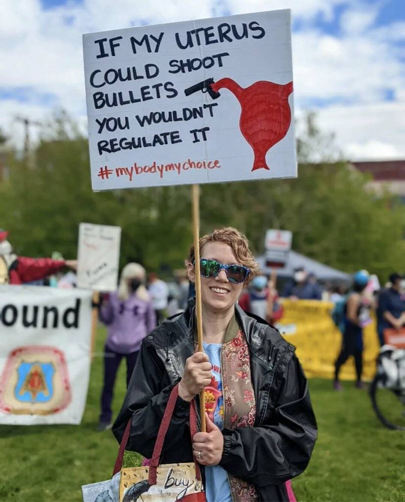 A woman smiles while holding a sign at the Cal Anderson Park reproductive rights protest on May 14, 2022. Hannah Saunders/Sound Publishing