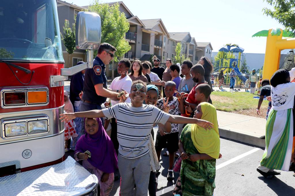 Capt. Brad Chaney hands out fire helmets and sticker badges to kids at the Kitts Corner Apartments on Aug. 2. Photo by Jack Reale