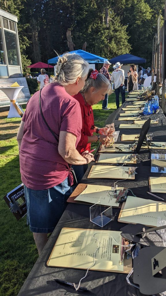 FUSION workers gathering silent auction bid results at FUSION Art Event August 3. Photo by Sarah Fox.