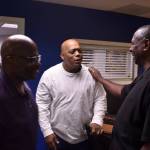 Pastor George Merriweather places his hand on the shoulder of Pastor Charles Allen, who is an Empowered Youth Project Mentor, during a conversation. Curtis Retic, board chair of the Good Shepherd Youth Outreach, stands in the doorway, and Louis Guiden walks by the group.