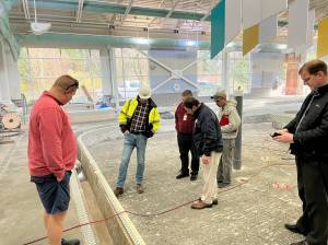 Federal Way Mayor Jim Ferrell and several others survey the work underway at the leisure pool on Dec. 9, which will need additional time for repair due to the discovery of corrosion in the concrete and rebar underneath its tiling. Photo courtesy of the City of Federal Way