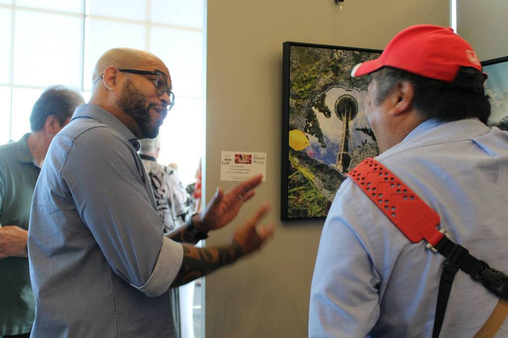 Photographer Robert Chism explains his work Space Needle Reflection to fellow photographer Bruce Honda at the Arts Explosion event. Alex Bruell / The Mirror