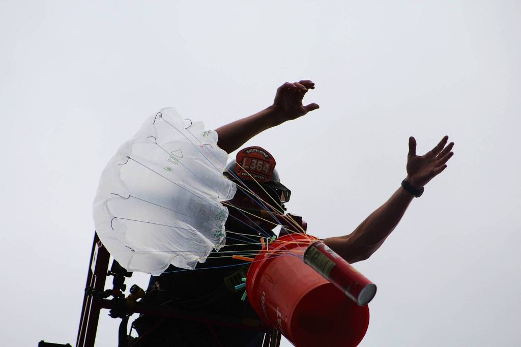 Firefighter Tyler Morris drops an egg payload to the ground from atop a South King Fire & Rescue ladder. Alex Bruell / The Mirror