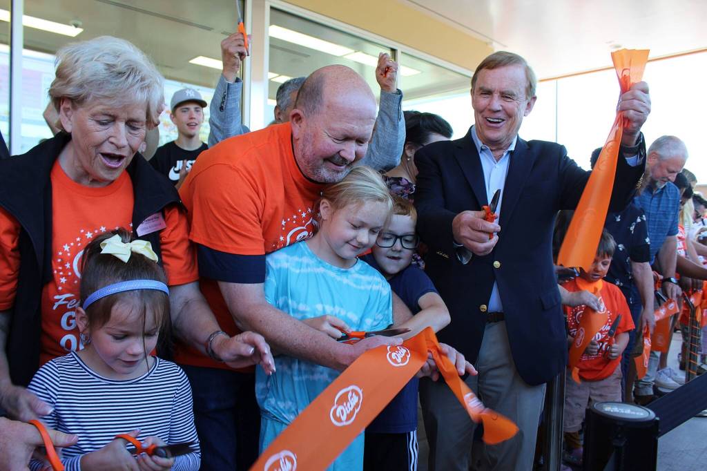 Federal Way City Councilmembers Linda Kochmar and Jack Walsh and King County Councilmember Pete von Reichbauer cut the ribbon on July 27 at the opening of Dicks Drive-In in Federal Way with a little help from some youngsters. Deputy Mayor Susan Honda, also cutting the ribbon, is just out of frame to the left. (Alex Bruell / The Mirror)