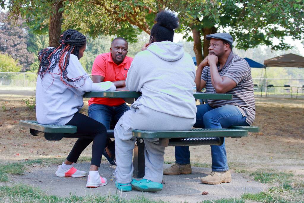 Fathers Dias Mobula and Bekmay Kayembe in a conversation with the next generation after the days environmental work has been completed. Photo by Keelin Everly-Lang / The Mirror
