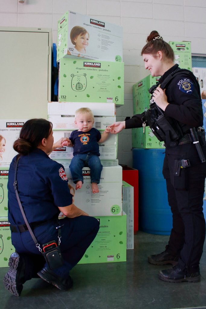 Photo by Keelin Everly-Lang / The Mirror
Captain Browning of South King Fire and Police Officer Britney Paul with Lieutenant Ann Hoags son celebrate the diapers purchased through community donations.