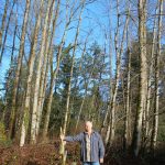 Loren Meiser holds a walking stick that he carved from one of the 50+ trees that used to fill his own property before a neighbors influence caused him to cut them down. (Photo by Keelin Everly-Lang / The Mirror)