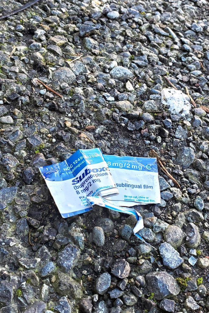 Outside the roundtable, a medication wrapper is in the parking lot of the recovery housing that is also on the property. Suboxone is medication that uses the same chemical compound as lifesaving Narcan to help those dealing with addiction to fentanyl in their recovery. Suboxone and Vivitrol were both discussed several times during the round table. Photo by Keelin Everly-Lang / The Mirror.