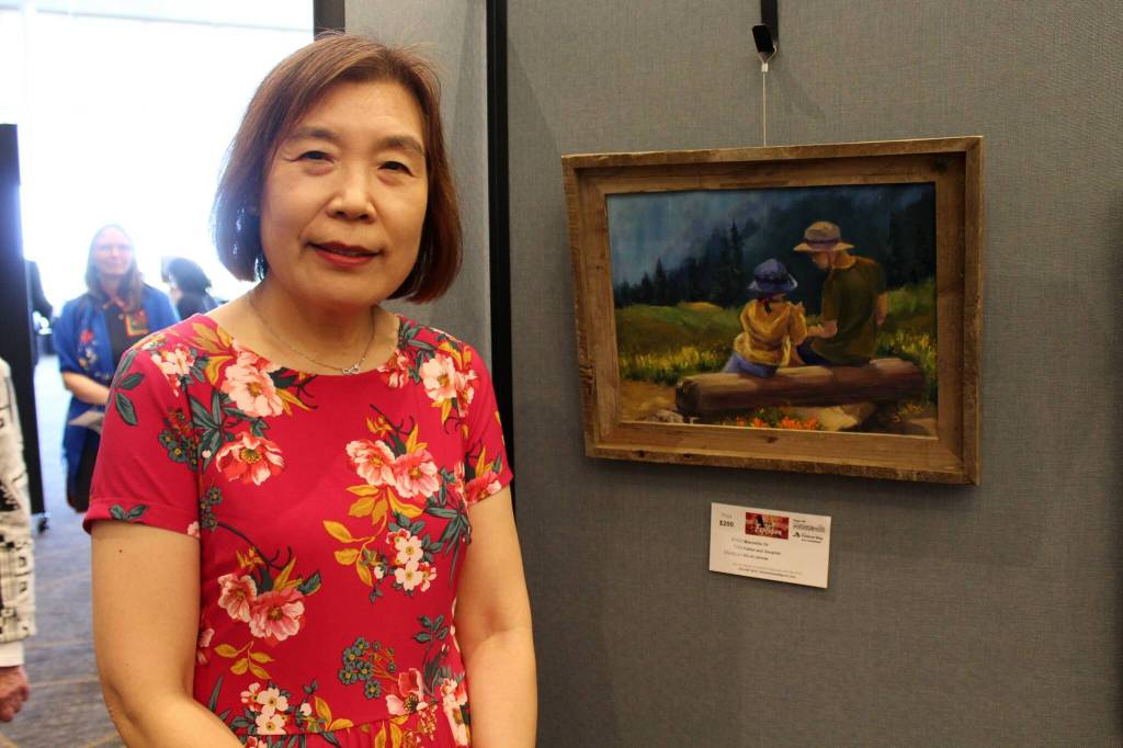 Mischellie Oh stands next to her painting Father and Daughter, which was inspired by a scene she came across during a hike in the Mt. Rainier area. Mirror file photo