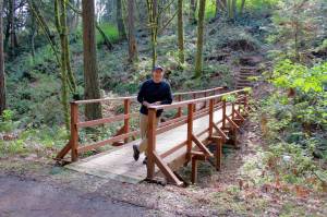 Josh Sutton of YMCA stands on a newly finished bridge that was one of nine projects completed by NOIA volunteers in September. Photo by Keelin Everly-Lang / The Mirror
