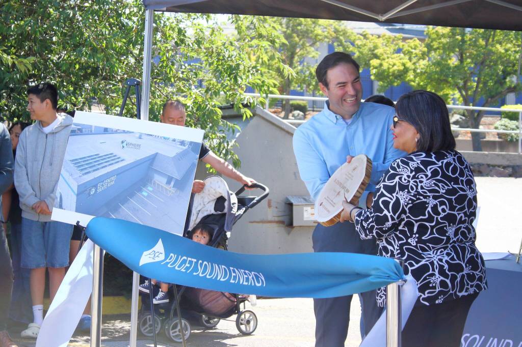 John Mannetti of PSE presents an award to Estela Ortega of El Centro de la Raza. The award was crafted from an upcycled utility pole. Photo by Keelin Everly-Lang / the Mirror