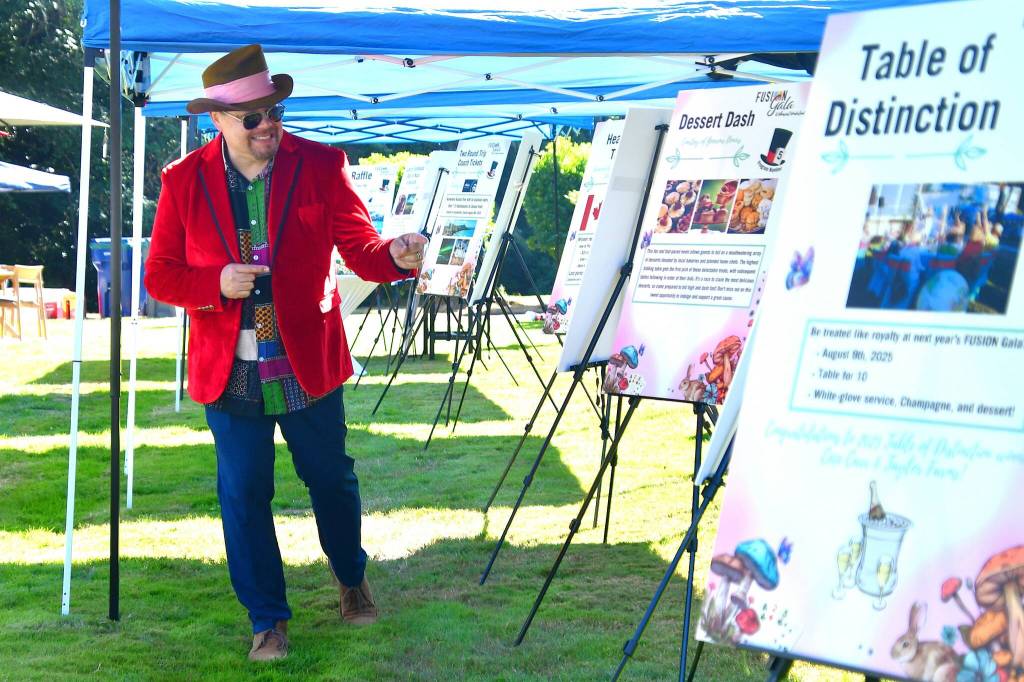 Guests not only dressed up in their tea party best - some emulated the Mad Hatter to get into the fun, like this guest who is showing off the prize packages for the auction. Photo by Bruce Honda.