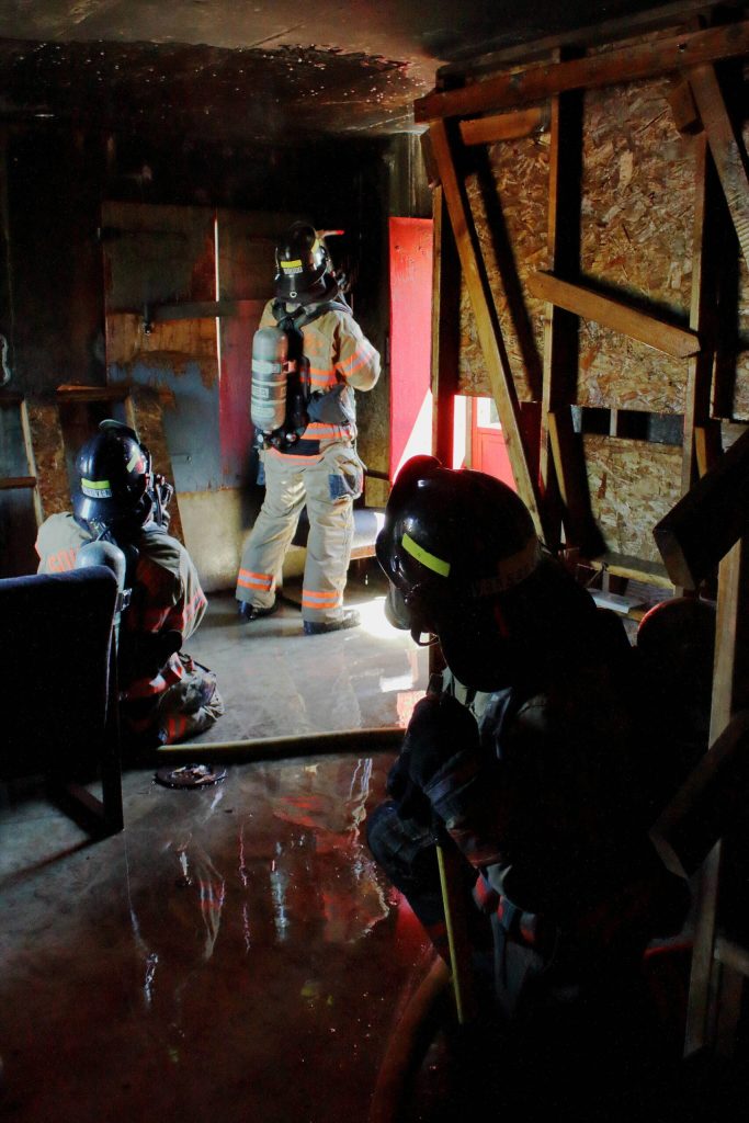 A probationary firefighter simulates breaking through a roof during a scenario of a fire in a multi-story building.