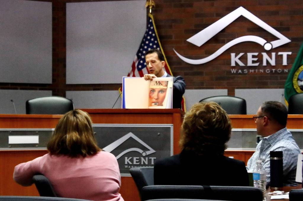 David Martin holds up a book that compiled a visual history of the fight to stop violence against women. In this reprinted cover of a Ms. Magazine, a womans face can be seen battered and bruised. Martin is chair of the DVI Task Force and a prosecuting attorney for King County.