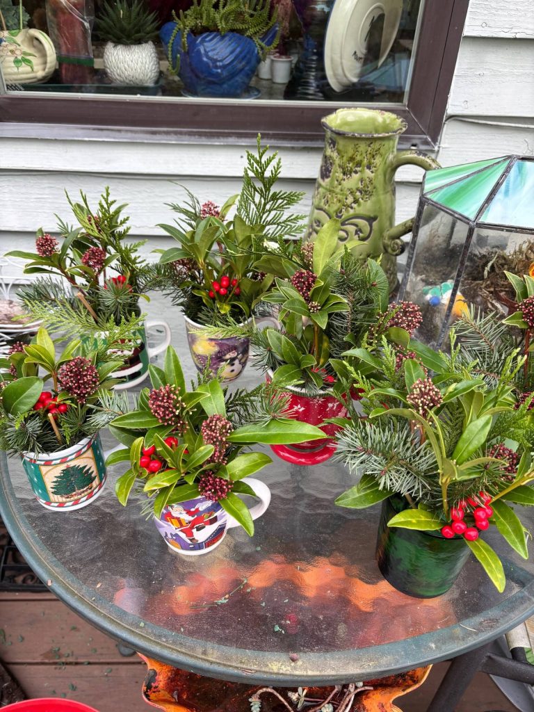 Greenery, festive leaves and holiday themed mugs come together to create holiday spirit in these floral arrangements created by the Marine Hills Garden Club. Photo provided by Debbie Angel