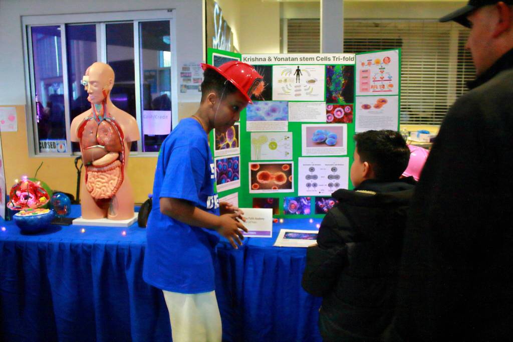A sixth-grader from the Federal Way Public Academy shares an enthusiastic and detailed explanation of current stem cell innovation research with a guest at the STEAM event.