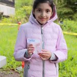 Student Sehaj from Meredith Hill Elementary holds a salmon fry in a cup as she gets ready to release it. Photo by Keelin Everly-Lang / the Mirror