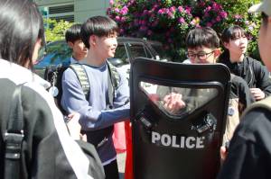 Students from Hachinohe, Japan, get an introduction to Federal Way and the United States by meeting police officers and holding riot shields. Photo by Keelin Everly-Lang / the Mirror