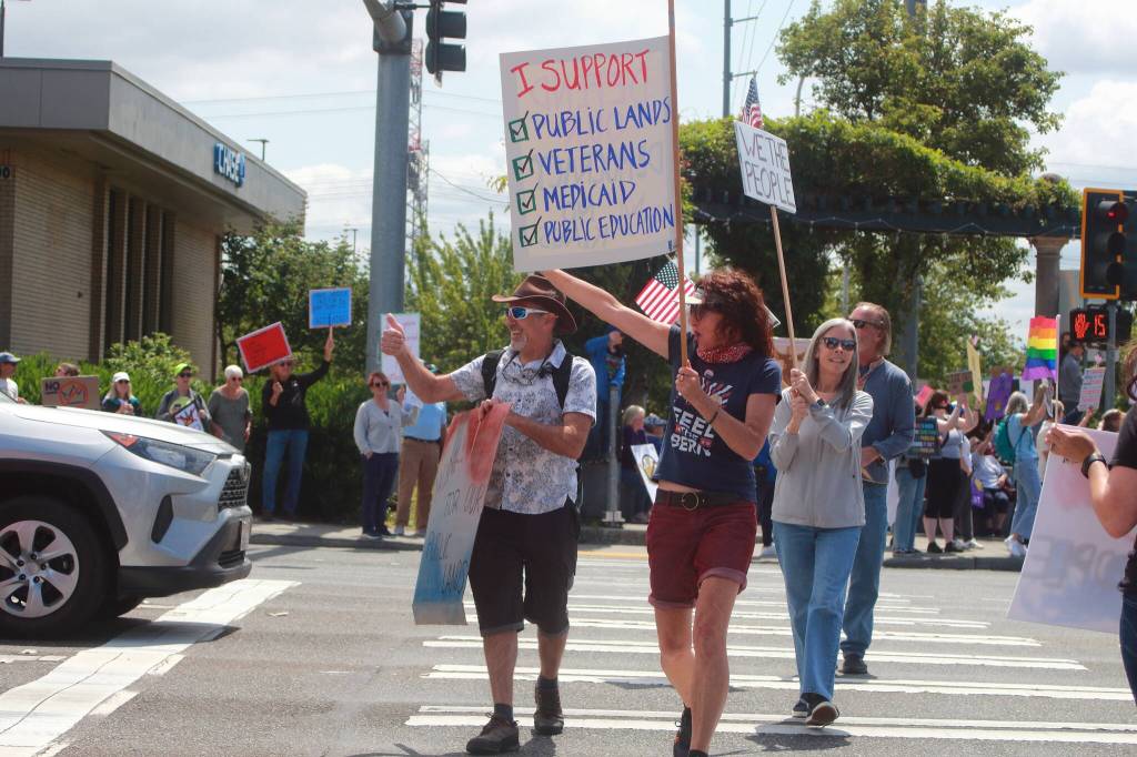 Demonstrators react to supportive honking from cars with a wave and a thumbs up as they cross the street during Saturdays No Kings demonstration in Federal Way. Photo by Keelin Everly-Lang/the Mirror