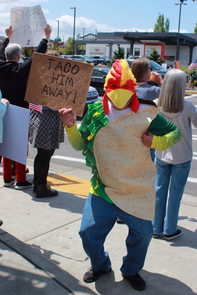 Several signs included references to TACO, an acronym that stands for Trump Always Chickens Out and has gained traction online since it was first used by Financial Times journalist Robert Armstrong in an opinion piece in early May. Photo by Keelin Everly-Lang/the Mirror