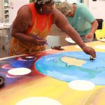 Deycha Nhtae works on the community mural at Saturdays Juneteenth event. Photo by Keelin Everly-Lang / the Mirror.