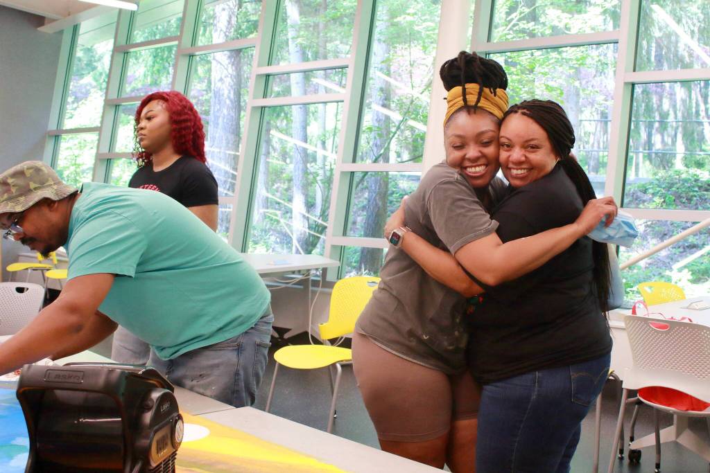 The theme of the community mural was family reunion and the painting party included this moment of joy between Jeneva and her mom. Photo by Keelin Everly-Lang / the Mirror.