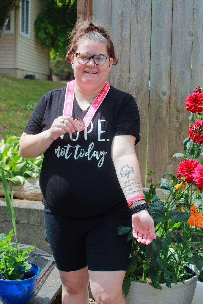 Athlete Sam Fine has competed in Special Olympics games for many years and even has the athlete oath tattooed on her arm. Here she shows off both the tattoo and her recently won third place medal for Level A soccer. Photo by Keelin Everly-Lang / the Mirror