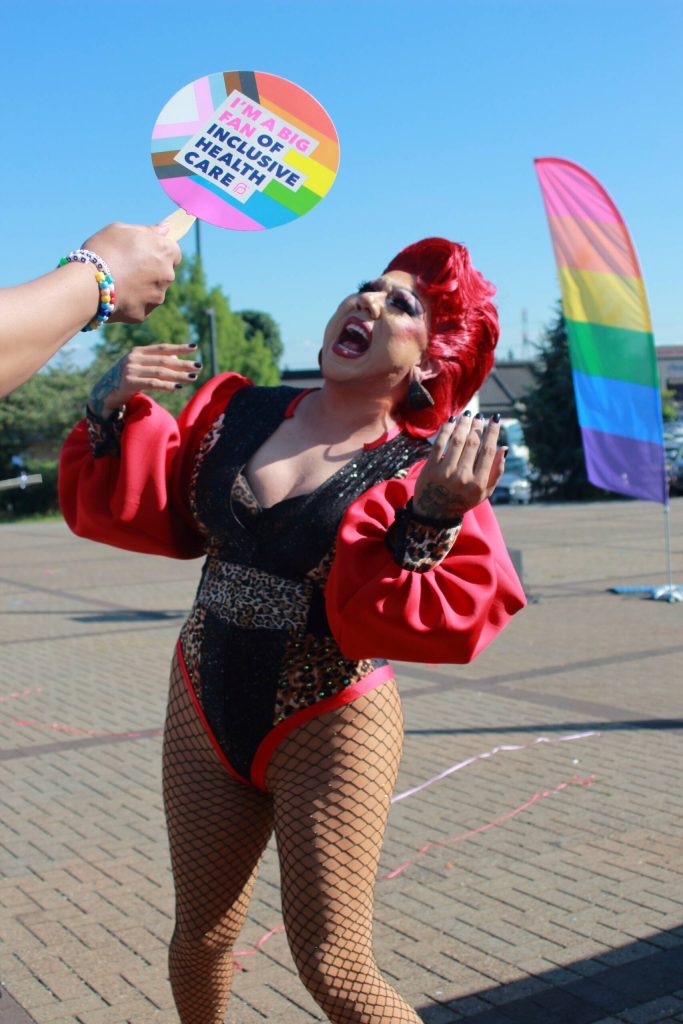 Holli B. Sinclair in her first performance of the set, getting a refreshing breeze from an audience member with a fan due to the high temperatures at Federal Way Pride. Photo by Keelin Everly-Lang / the Mirror.