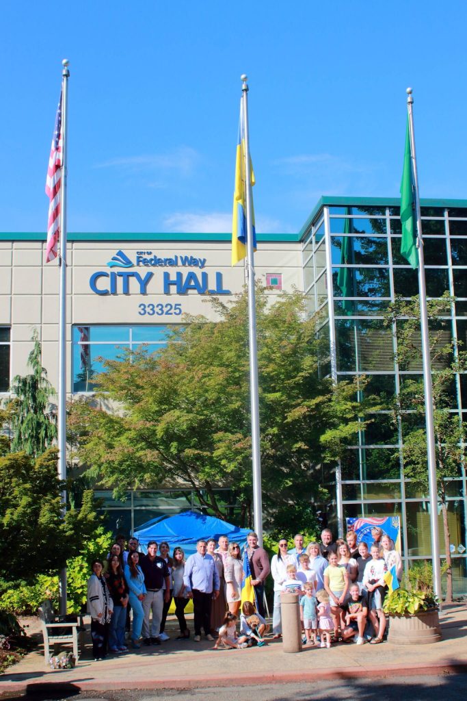 Ukrainian community members and local leaders pose with the Ukrainian flag after it is raised for the first time at city hall. Photos by Keelin Everly-Lang / the Mirror