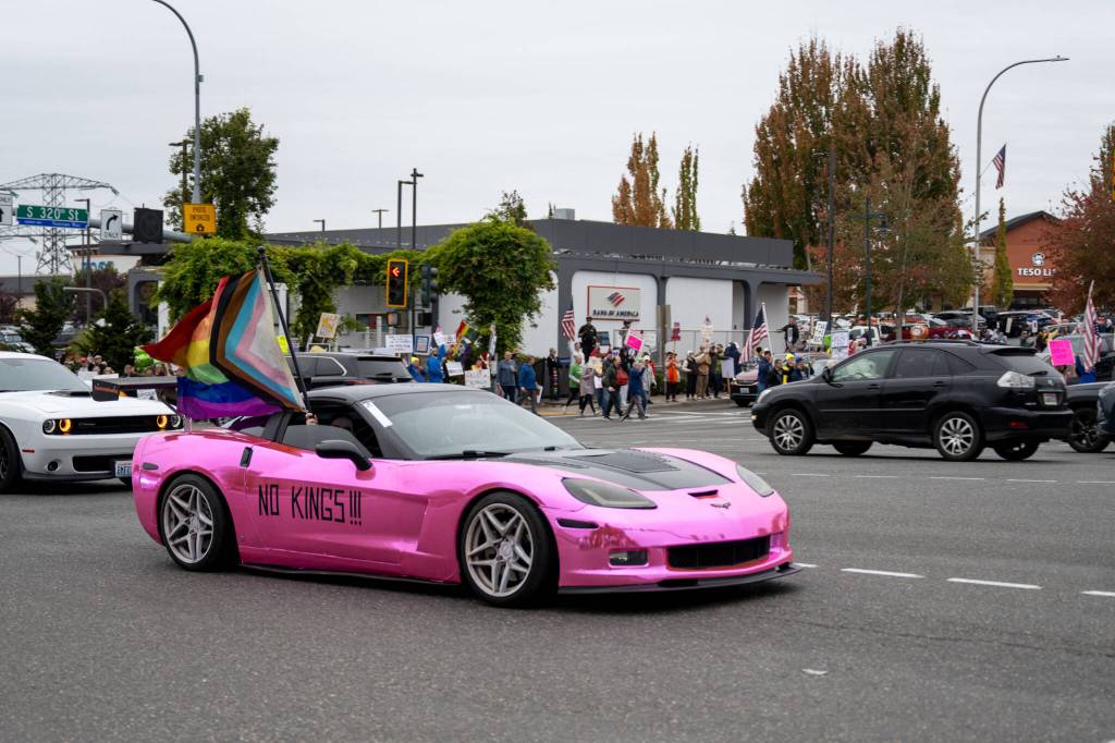 While many drivers shared their opinions about the No Kings protest in Federal Way through either supportive honks or through unsupportive middle fingers while passing by Saturdays protest, this driver made their message known by waving the progressive LGBTQ+ flag out the window and emblazoning NO KINGS on the side of their hot pink vehicle. Photo by Rachel Jones