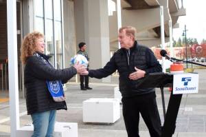 King County Councilmember Pete von Reichbauer hands a soccer ball to Auburn Mayor Nancy Backus at a press event at the Federal Way transit station on Oct. 30 to kick off simulated service of the new Federal Way Link Extension. For the next month, the trains will run their regular schedule without passengers to ensure the trains are ready to go live starting Dec. 6. Photo by Keelin Everly-Lang / the Mirror