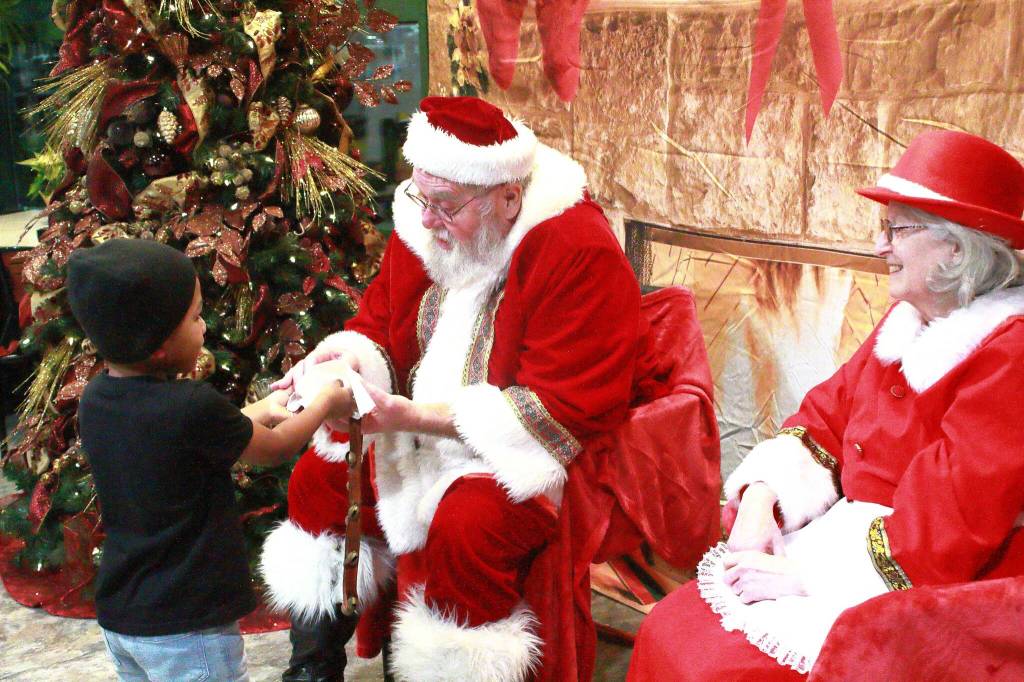 A young visitor gives a Christmas cookie to Santa at St. Francis Hospital. Photo by Keelin Everly-Lang / the Mirror