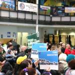 Community members hold signs calling for the passage of the Millionaires Tax at the Feb. 21 town hall. Courtesy photo.