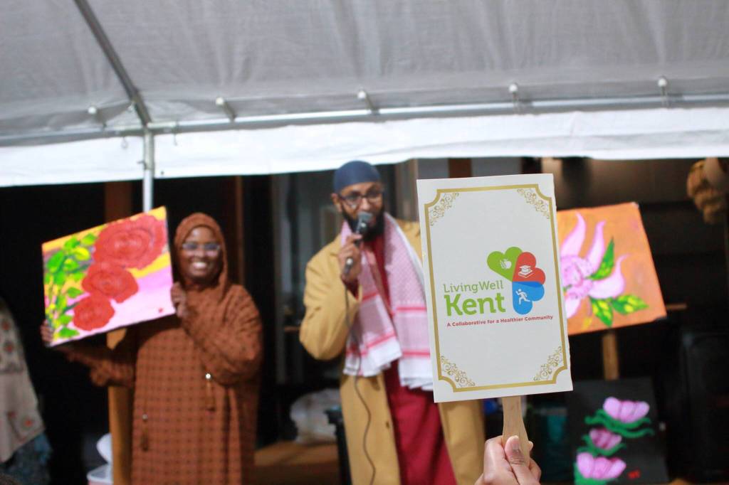 An attendee bids on paintings done by youth in the community to raise money for the House of Dua.