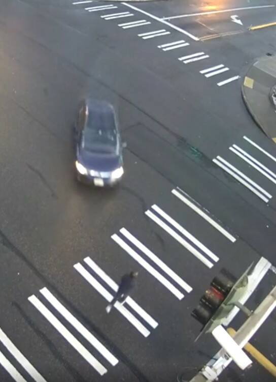 A woman crosses the street right before being hit by the dark car on Feb. 26, 2024, at the intersection of 19th Avenue SW and SW Campus Drive. Photo from SafeCity footage