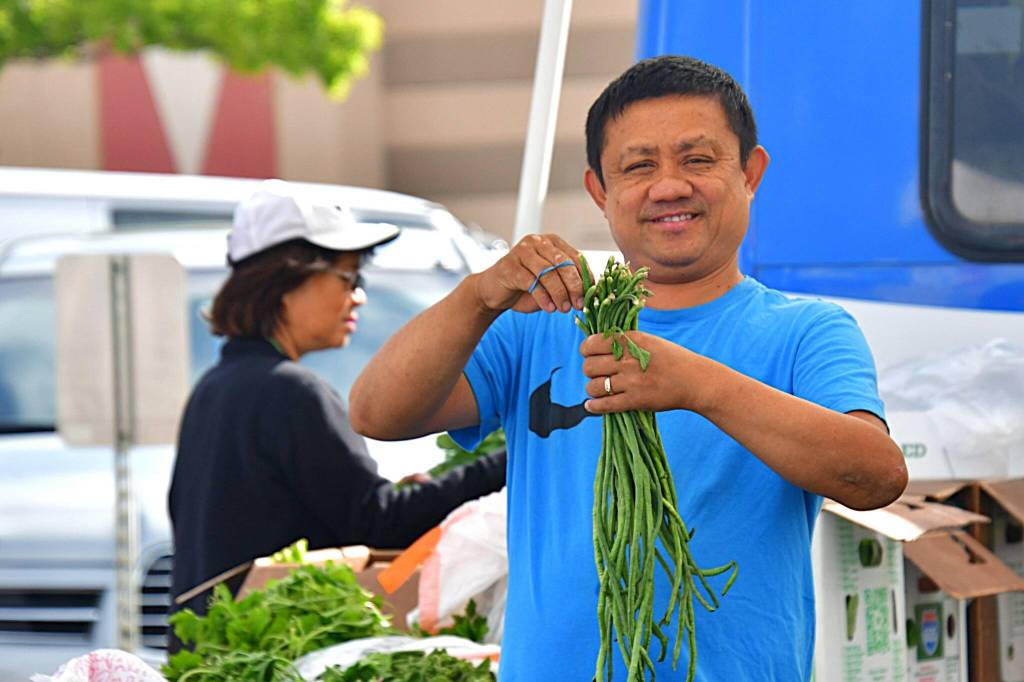 Photo by Bruce Honda
A vendor preps vegetables for sale at a Federal Way Farmers Market in 2025.